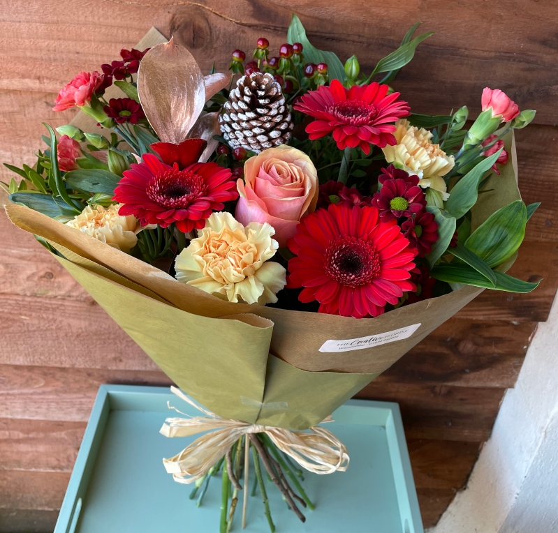 Christmas bouquet, simply wrapped in paper with a raffia bow.