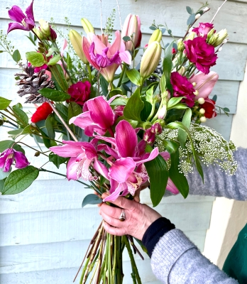 Hand tied festive bouquet with orchids, lilies and a mix of luxurious flowers.