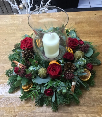 Hurricane lamp table decoration with fresh red roses and candle.